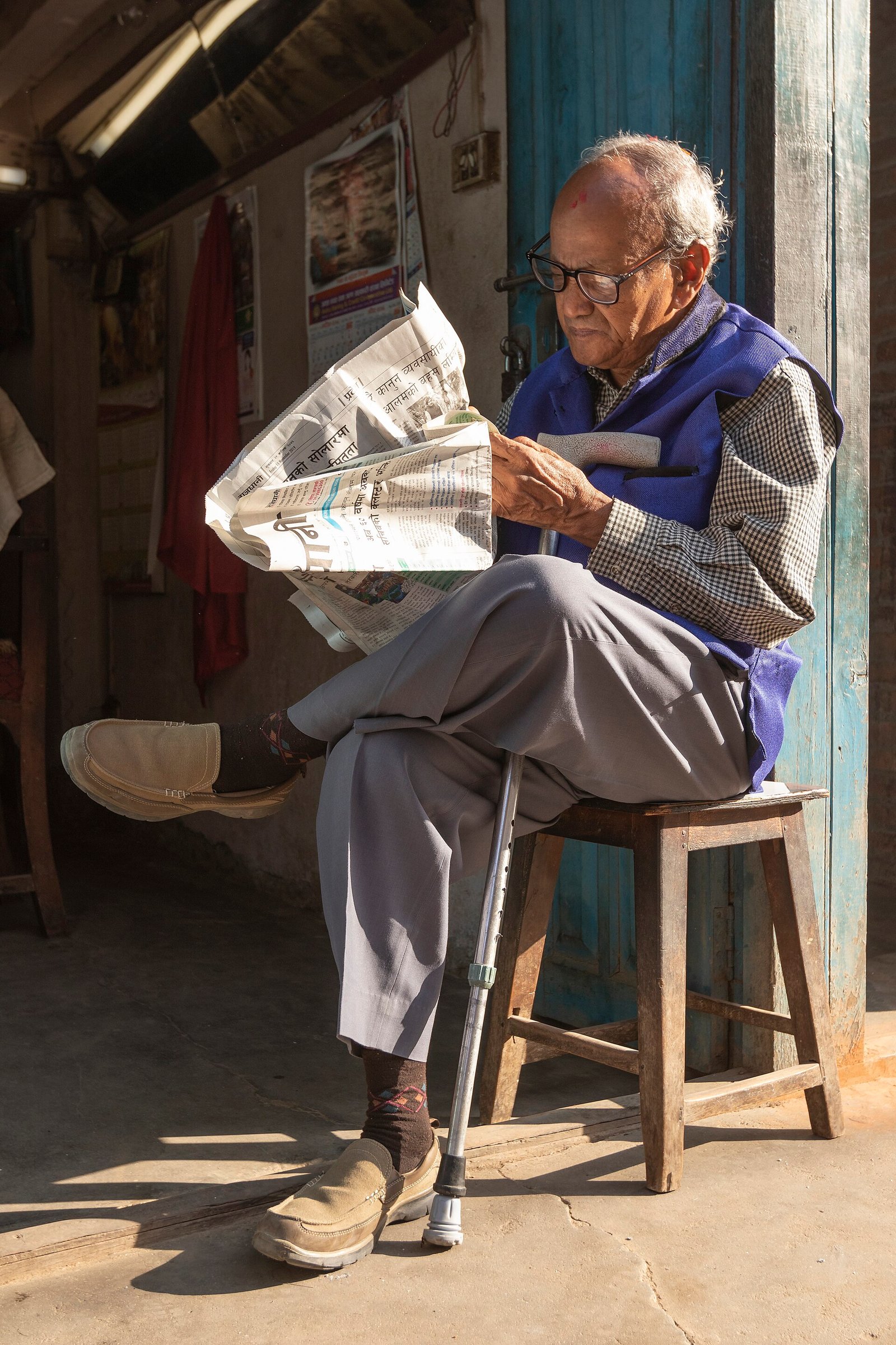 An elderly Nepali man reading at home